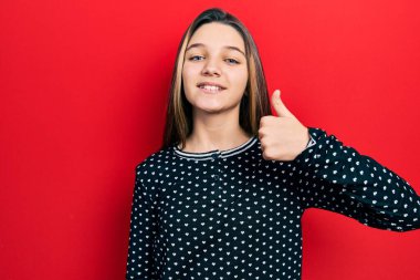 Genç esmer kız güler yüzlü, neşeli ve pozitif, başparmağıyla mükemmel ve onay işareti yapıyor. 