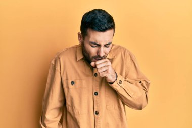 Günlük kıyafetler giyen genç İspanyol adam kendini iyi hissetmiyor ve soğuk algınlığı veya bronşitin belirtisi olarak öksürüyor. sağlık hizmeti kavramı. 