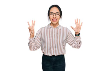 Gündelik kıyafetler giyen ve gözlük takan genç İspanyol kız sekiz numaralı parmaklarını gösterip işaret ederken kendinden emin ve mutlu gülümsüyor.. 