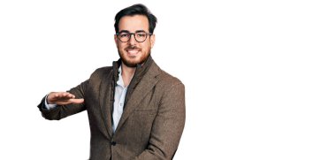 İş ceketi giyen ve büyük boy ve ölçü işareti gösteren el hareketleriyle el kol hareketi yapan İspanyol genç bir adam. Kameraya bakıp gülümsüyor. ölçüm kavramı. 