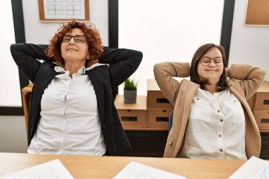 Ofiste çalışan iki kadın grubu. Olgun kadın ve Down sendromlu kız kapsayıcı takım çalışması yapıyor..