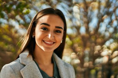 Genç İspanyol kız parkta mutlu bir şekilde gülümsüyor..