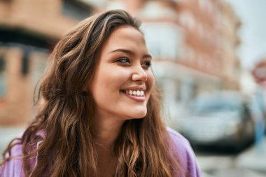 Genç İspanyol kadın gülümseyerek şehirde mutlu mesut dikiliyor..