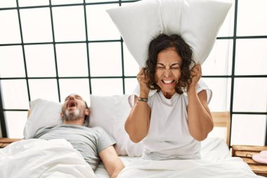 Orta yaşlı horlayan İspanyol bir adam ve yatak odasında yastıkla kulaklarını kapatan kızgın bir kadın..