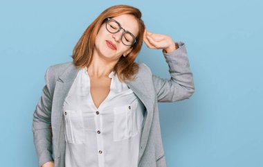 İş tarzı giyinmiş, gözlük takan, yorgun, rahat, uykulu ve sabahın erken saatlerinde esnemekte olan beyaz bir kadın. 