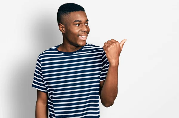 Joven Afroamericano Hombre Vistiendo Casual Rayas Camiseta Apuntando Pulgar Hacia —  Fotos de Stock