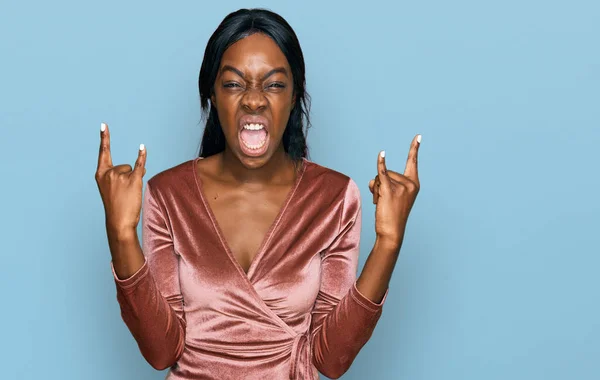セクシーなパーティードレスを身に着けている若いアフリカ系アメリカ人女性が手を上げてロックシンボルをやって狂気の表情で叫んでいます 音楽スター 重い概念は — ストック写真