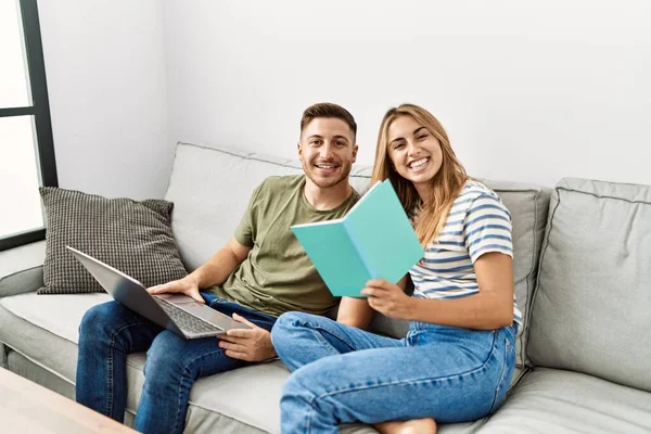 Unga Latinamerikanska Par Använder Laptop Och Läser Bok Sitter Soffan — Stockfoto