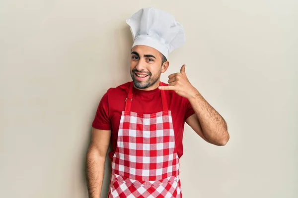 Young Hispanic Man Wearing Baker Uniform Smiling Doing Phone Gesture — Stock Photo, Image