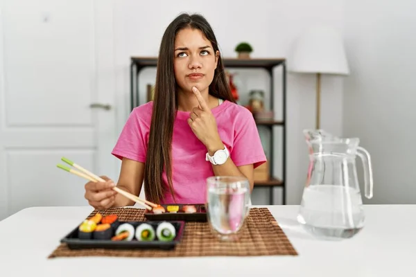 若いですブルネット女性食べる寿司箸を使用して思考濃縮約疑問について指であごと疑問に思って検索 — ストック写真