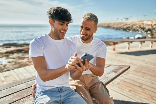 Joven Pareja Gay Sonriendo Feliz Usando Smartphone Playa —  Fotos de Stock