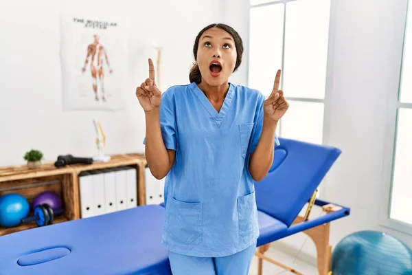 Красивая Латиноамериканка Физиотерапевт Клинике Лечению Боли Удивлена Удивлена Глядя Вверх — стоковое фото