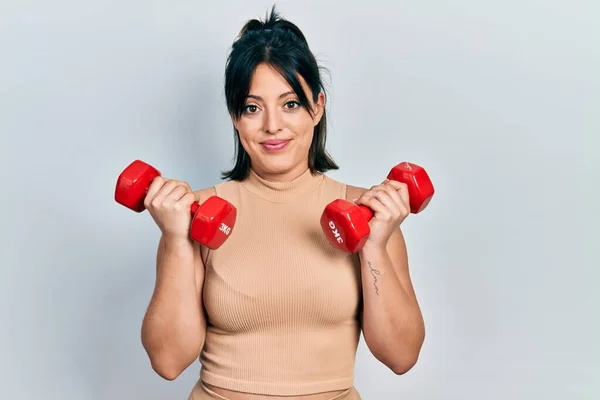 Young Hispanic Woman Wearing Sportswear Using Dumbbells Relaxed Serious Expression — Stock Photo, Image