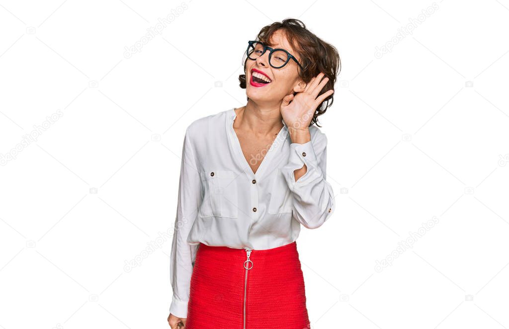 Young hispanic woman wearing business style and glasses smiling with hand over ear listening an hearing to rumor or gossip. deafness concept. 