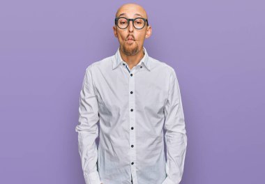 Sakallı, iş gömleği giyen, gözlüklü, dudağıyla balık suratlı çılgın ve komik bir jest yapan kel bir adam. Komik ifade. 