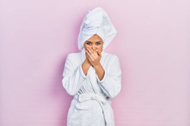 Duş havlusu şapkası ve bornoz takan genç İspanyol kız yanlışlıkla ağzı ellerle kapatmış. gizli kavram. 