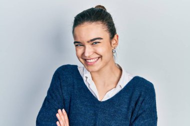 Sıradan kıyafetler giyen, kollarını kavuşturup kameraya gülümseyen beyaz bir kız. pozitif kişi. 