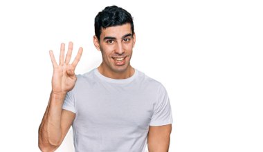 Yakışıklı, beyaz tişört giyen, dört numaralı parmaklarını gösterip, gülümseyen, kendinden emin ve mutlu bir İspanyol.. 