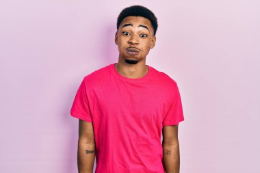 Casua tişörtü giyen genç Afro-Amerikan bir adam komik suratıyla yanaklarını şişiriyor. Havayla şişmiş ağız, çılgın bir ifade.. 