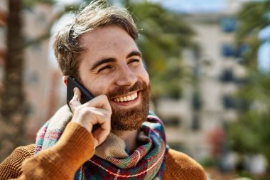 Beyaz sakallı bir adam güneşli bir günde telefonda konuşuyor.