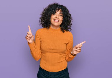 Gündelik giysiler giymiş, kendine güvenen, parmaklarını farklı yönlere çeviren İspanyol bir kadın. reklam için kopyalama alanı 