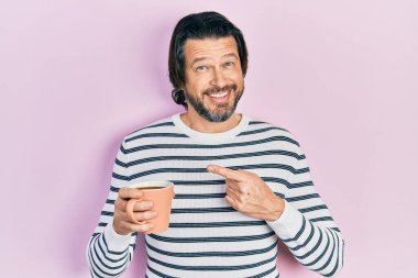 Orta yaşlı beyaz bir adam bir fincan kahve içiyor mutlu bir şekilde el ve parmak işareti yapıyor. 