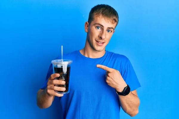 Homem Caucasiano Jovem Bebendo Copo Bebida Refrigerante Sorrindo Feliz Apontando — Fotografia de Stock