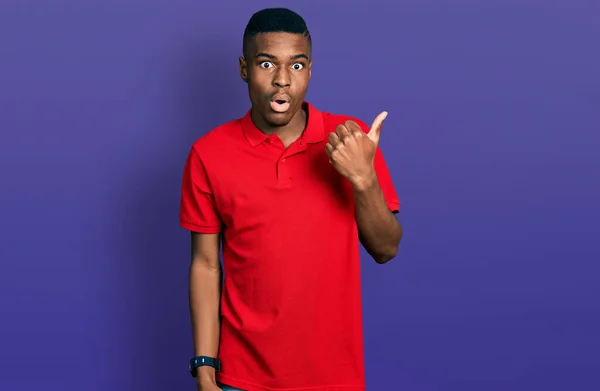 若いアフリカ系アメリカ人の男を着てカジュアルな赤いTシャツ驚くべきポインティングで手指で側面に オープン口驚きの式 — ストック写真