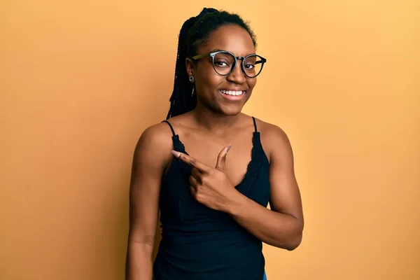 Afroamerykanka Plecionymi Włosami Ubrana Luźne Ubrania Okulary Uśmiechnięta Radosna Wskazując — Zdjęcie stockowe