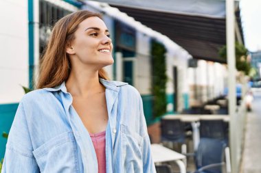 Genç İspanyol kız gülümseyerek şehirde mutlu mesut dikiliyor..