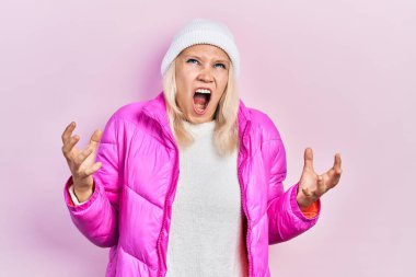 Güzel, beyaz, sarışın kadın yün şapka ve kışlık palto giyiyor. Deli gibi bağırıyor ve agresif bir ifade ve kollarla bağırıyor. hüsran kavramı. 