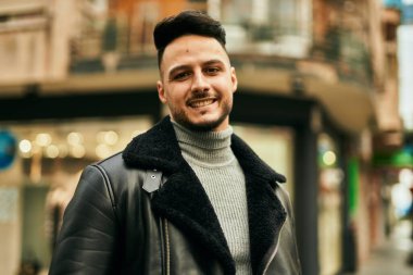 Genç Arap adam gülümsüyor, mutlu bir şekilde şehirde duruyor..