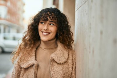 Genç İspanyol kadın gülümseyerek şehirde mutlu mesut dikiliyor.