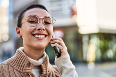 Kısa saçlı, gülümseyen, telefonda konuşan genç İspanyol kadın.