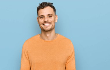 Yüzünde mutlu ve havalı bir gülümseme olan sıradan kıyafetler giyen genç İspanyol bir adam. şanslı kişi. 