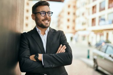 Kollarını kavuşturmuş genç İspanyol işadamı şehirde mutlu bir şekilde gülümsüyor..