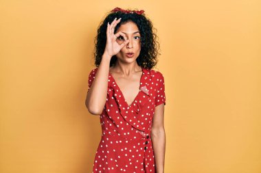 Yazlık elbise giyen genç Latin kız şaşırmış yüz ifadesiyle şok olmuş, parmaklarından bakan gözler. İnançsız ifade. 