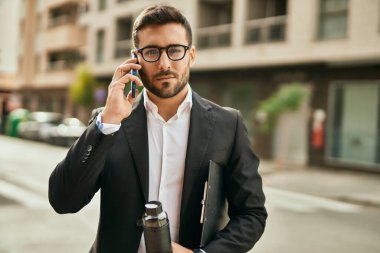 Genç İspanyol iş adamı ciddi bir ifadeyle şehirdeki akıllı telefondan konuşuyor..