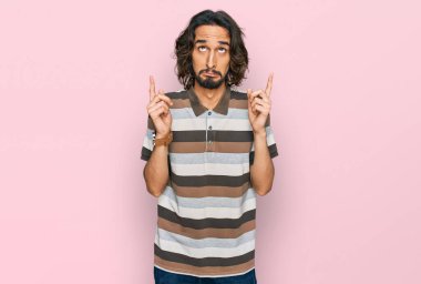 Gündelik kıyafetler giyen genç İspanyol adam üzgün ve üzgün görünüyor, parmaklarıyla yön gösteriyor, mutsuz ve depresif.. 