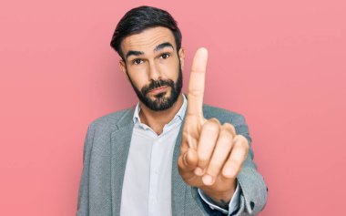 İş kıyafetleri giymiş genç İspanyol bir adam parmağını kaldırmış ve kızgın bir ifadeyle işaret ediyor. Hiç hareket göstermiyor. 