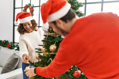 Orta yaşlı İspanyol çift gülümsüyor. Mutlu noel ağacı süslüyor evde..