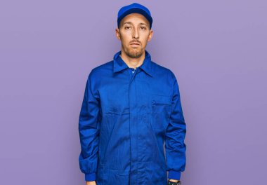 Sakallı, işçi tulumu giyen kel adam yüzünde ciddi bir ifadeyle rahatlamış. Basit ve doğal bir şekilde kameraya bakıyorsun.. 