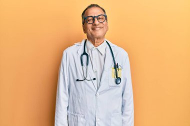 Doktor önlüğü ve steteskop giyen orta yaşlı Hintli adam yüzünde ciddi bir ifadeyle rahatlamış. Basit ve doğal bir şekilde kameraya bakıyorsun.. 