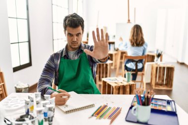 Sanat stüdyosundaki genç sanatçı avuç içi hareketlerini durduruyor. Öfkeli ve hayal kırıklığı dolu bir ifade. 