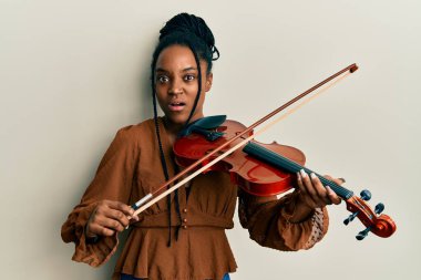 Saçları örgülü, keman çalan, kafası karışık Afrikalı Amerikalı bir kadın. şüphe kavramı. 