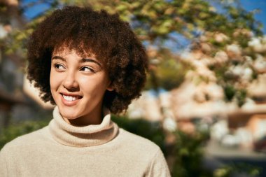 Genç İspanyol kız gülümseyerek şehirde mutlu mesut dikiliyor..