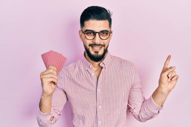 Poker kartları tutan yakışıklı adam mutlu bir şekilde gülümsüyor. 