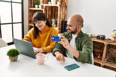 Genç İspanyol çift dizüstü bilgisayar ve kredi kartı kullanarak mutlu bir şekilde gülümsüyor..