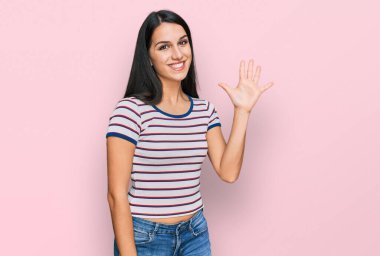 Gündelik çizgili tişört giyen genç İspanyol kız beş numarayı gösterip işaret ederken kendinden emin ve mutlu bir şekilde gülümsüyor.. 