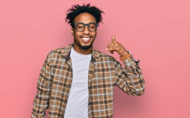 Sakallı ve gözlüklü genç Afro-Amerikalı adam telefonla el ve parmaklarıyla telefonla konuşuyor gibi gülümsüyor. iletişim kavramları. 